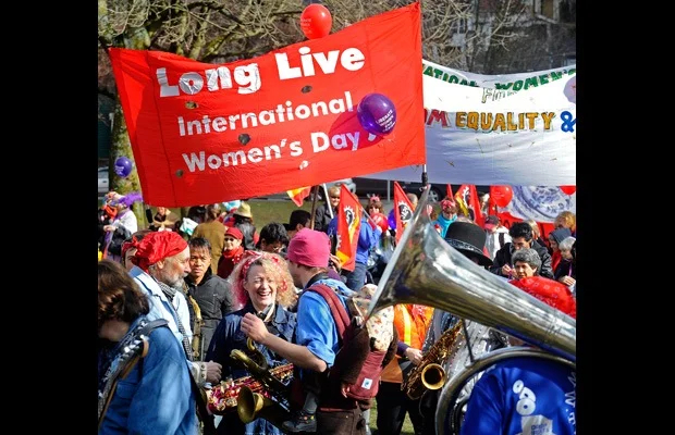 Men and women celebrate International Women's Day along Commercial Drive in Vancouver, Canada